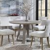 A stylish round and richly grained oak veneer dining table by Uttermost with an elm wood trestle base