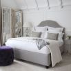 Designer bed with an elegant, curved headboard and stud detailing 