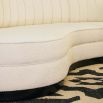 A luxurious boucle-upholstered curved sofa with piped details and a dark wenge plinth base