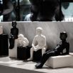 A small ceramic sculpture of a man sat on a black black 