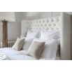 Grand luxury upholstered bed, with deep buttoned headboard, sharp wings and piping detail