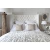 Grand luxury upholstered bed, with deep buttoned headboard, sharp wings and piping detail