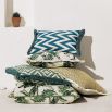 A teal, zigzag patterned cushion with matching fringe details.