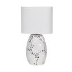 An elegant table lamp with a lace effect and white linen shade