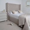 Grand luxury upholstered bed, with deep buttoned headboard, sharp wings and piping detail