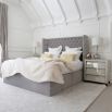 Grand luxury upholstered bed, with deep buttoned headboard, sharp wings and piping detail