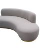 A luxury curved sofa by Liang & Eimil with a grey boucle upholstery and brushed brass base