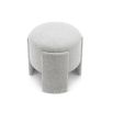 Small round ottoman upholstered in off-white fabric with wide legs overlapping the seat