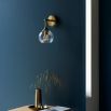 Wall sconce with singular twisted glass globe and brass fixture
