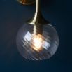 Wall sconce with singular twisted glass globe and brass fixture