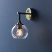 Wall sconce with singular twisted glass globe and nickel fixture