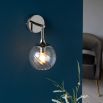 Wall sconce with singular twisted glass globe and nickel fixture