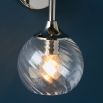 Wall sconce with singular twisted glass globe and nickel fixture