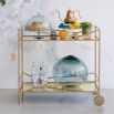 A luxury bar cart by Caracole with a glamorous gold finish