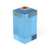 A glamorous candleholder by Jonathan Adler featuring a blue acrylic block fitted with a solid brass candleholder