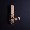 A glamorous brass wall lamp with a transparent glass lampshade