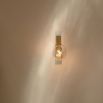A glamorous brass wall lamp with a transparent glass lampshade