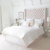 Luxury hotel-style bed with tall deep buttoned headboard and stud detailing