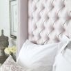 Luxury hotel-style bed with tall deep buttoned headboard and stud detailing