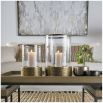 Lantern with textured brass base and cylindrical glass frame