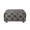 A luxurious dark grey velvet pouffe with deep buttoning