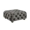 A luxurious dark grey velvet pouffe with deep buttoning