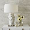 A stylish side lamp by Uttermost with a white ceramic sculptural base and white textured cotton shade