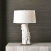 A stylish side lamp by Uttermost with a white ceramic sculptural base and white textured cotton shade