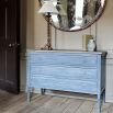 A gorgeous chest of drawers with a distressed grey finish and natural wood top 