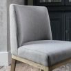 Grey upholstered dining chair with warm oak frame