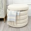 A luxurious boucle cream upholstered ottoman with storage space