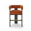 A luxury counter stool with a red and orange velvet upholstery and brass detailing