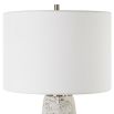 This tapered ceramic lamp has a distressed off-white finish, brushed nickel accents, and a white linen shade, adding timeless elegance to any space.