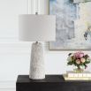 This tapered ceramic lamp has a distressed off-white finish, brushed nickel accents, and a white linen shade, adding timeless elegance to any space.