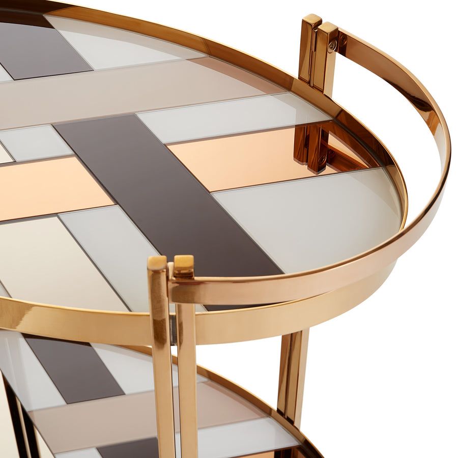 The Chambeige Bar Cart features back-painted glass shelves in a captivating Chambeige hue, framed by polished brass for a glamorous touch.