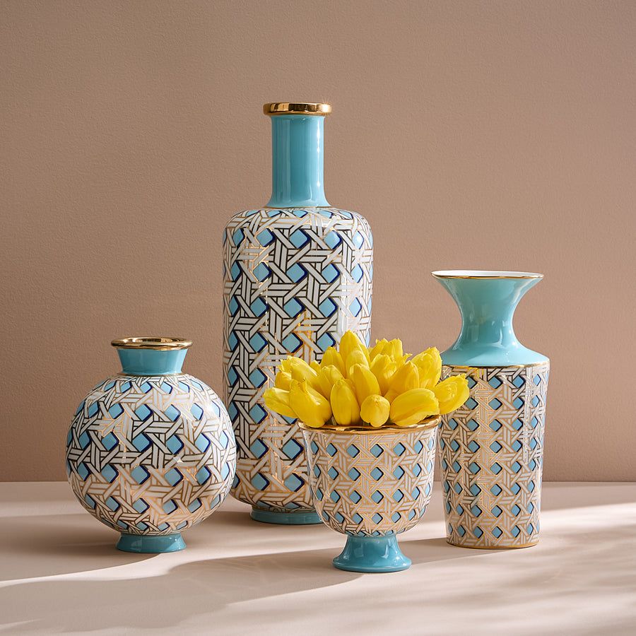 A porcelain pedestal bowl with a light blue glaze and gold caning, combining preppy sophistication with modern elegance.