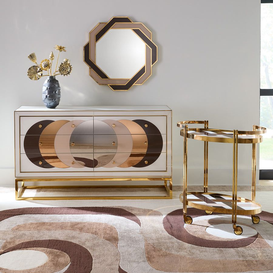 The Chambeige Bar Cart features back-painted glass shelves in a captivating Chambeige hue, framed by polished brass for a glamorous touch.