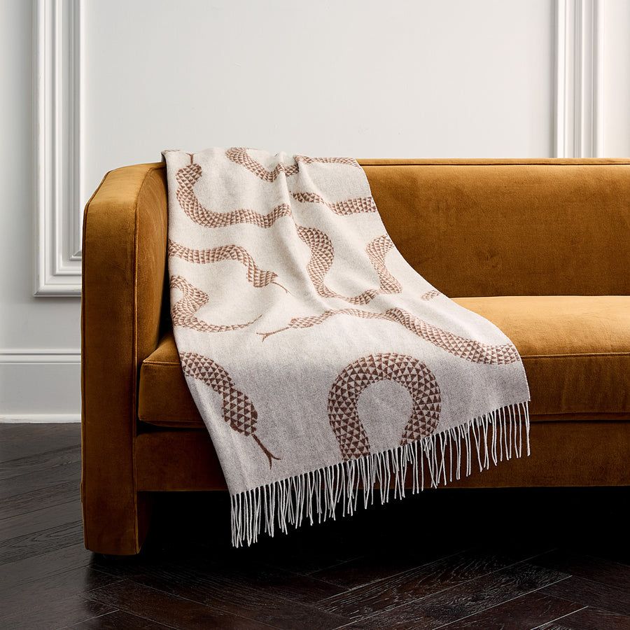The Eden Merino Wool Throw is handcrafted from soft Merino wool, featuring signature serpents in a neutral palette for luxurious layering.