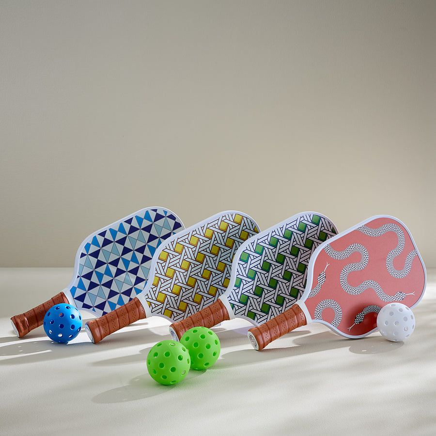 A stylish pickleball set with serpent-printed paddles, leather-wrapped handles, and a chic retro design, complete with two balls.