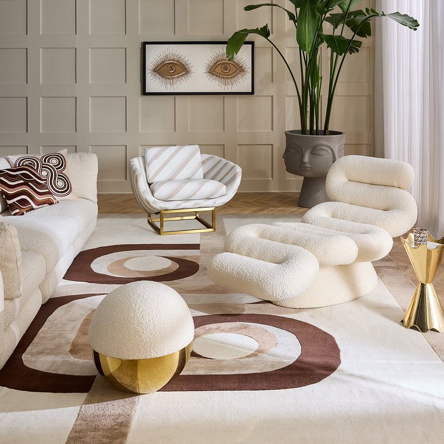 The Beaumont Lounge Chair combines minimalist design with luxurious comfort, featuring a sculptural brass base and elegant upholstery in velvet or bouclé.