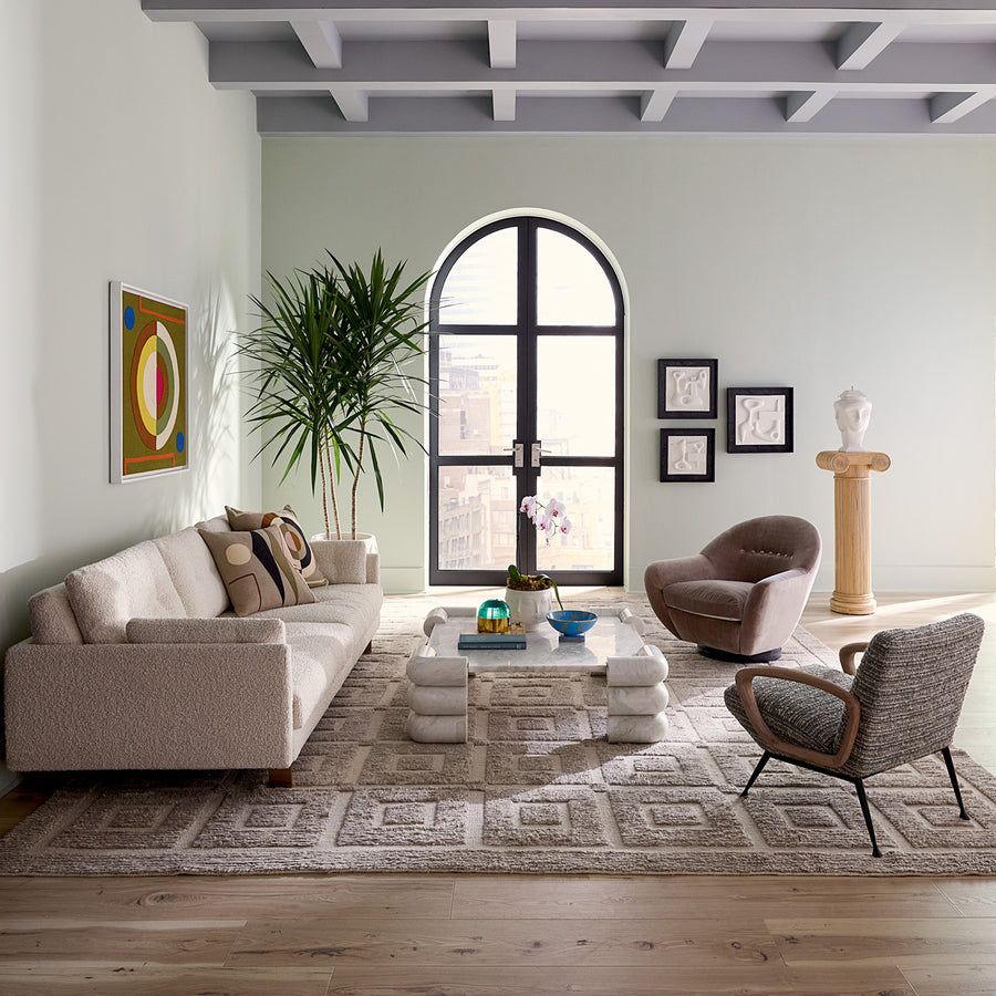 The Gainsbourg Lounge Chair is a vintage-inspired piece with a cushy seat, cerused ash wood arms, and blackened metal legs, perfect for pairing with a sofa.