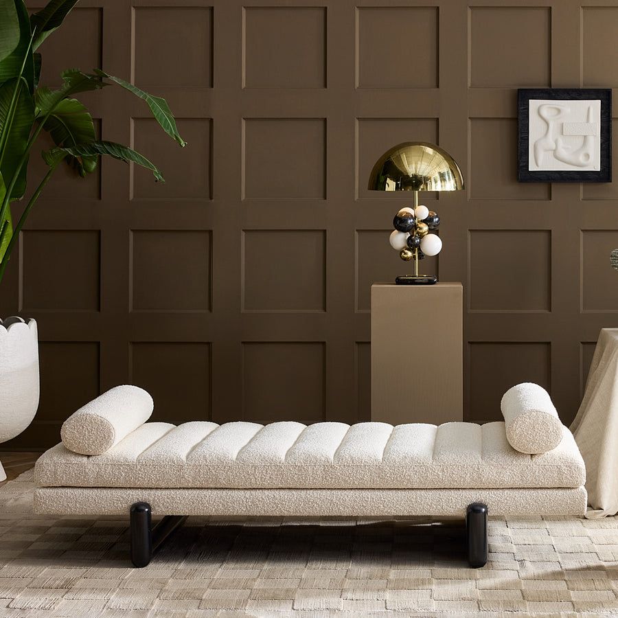 The Aspen Daybed features a lozenge-inspired design with ebonized legs and channelled bouclé cushions, offering style and comfort for any space.