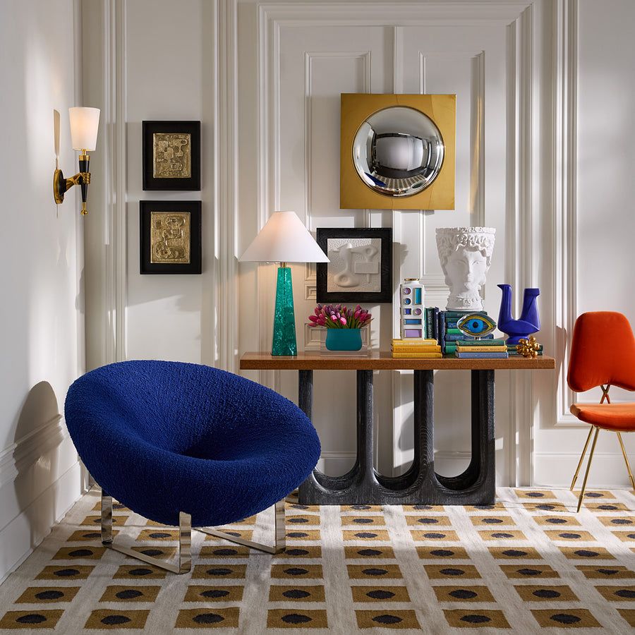 The Saturn Lounge Chair adds vibrant energy to any room with its cobalt bouclé upholstery and shiny nickel base, embodying modern luxury.