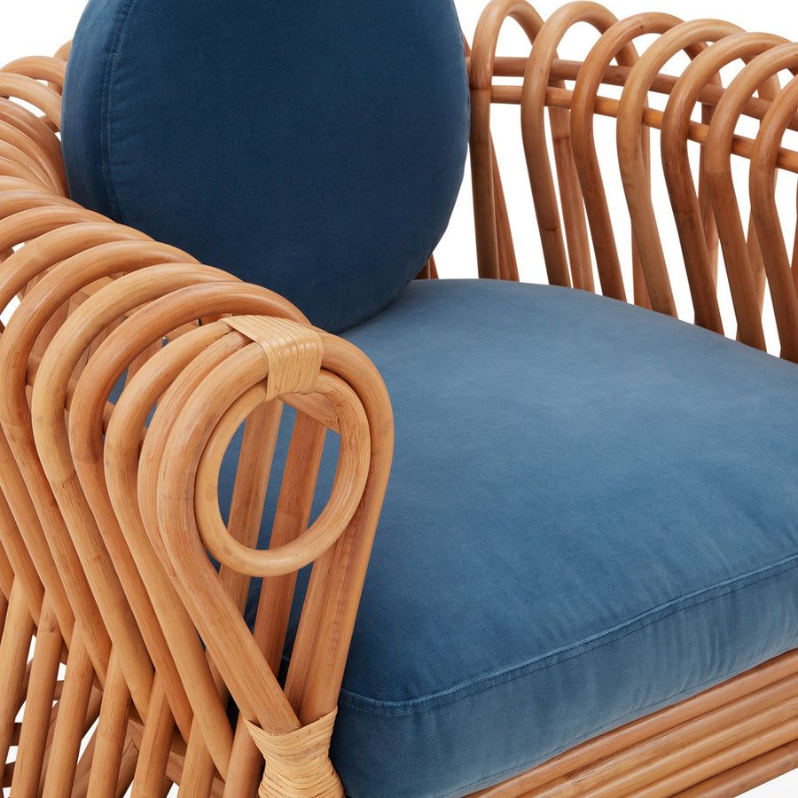 The St Tropez Lounge Chair blends coastal charm and haute couture with hand-coiled reeds and blue velvet cushions, finished with satin lacquer.