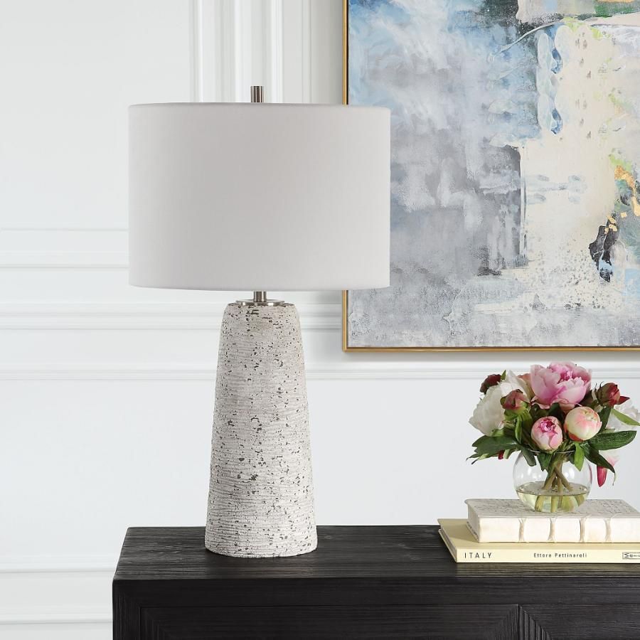 This tapered ceramic lamp has a distressed off-white finish, brushed nickel accents, and a white linen shade, adding timeless elegance to any space.