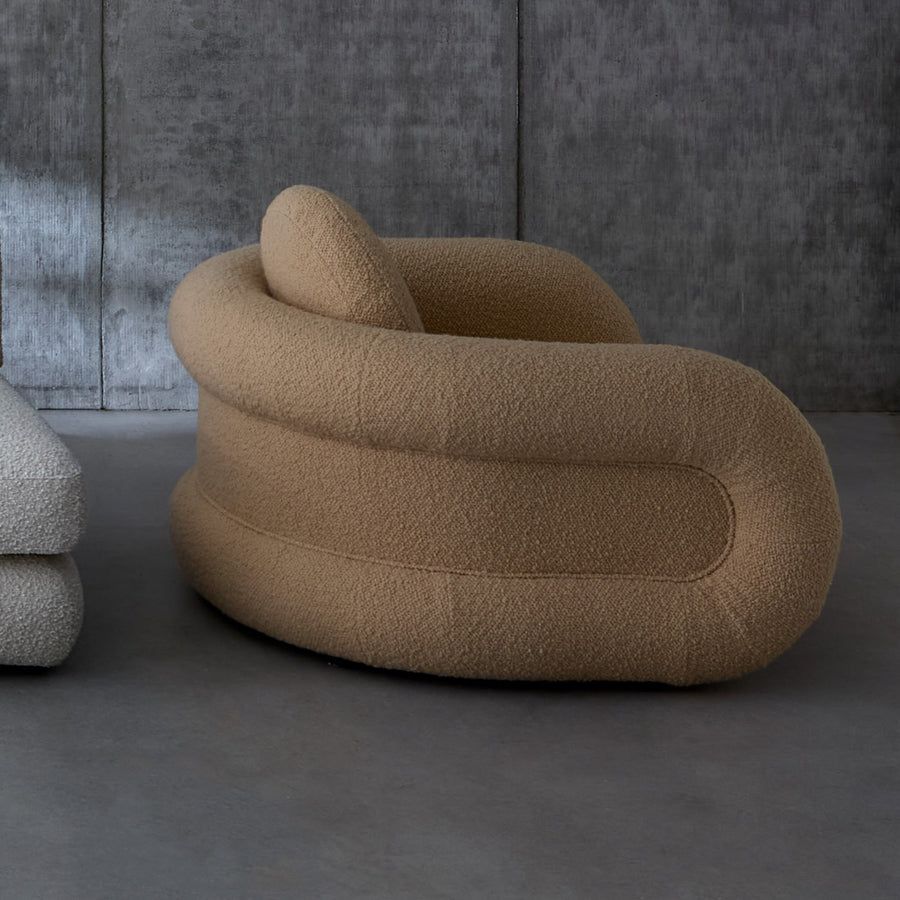 The Pompidou Lounge Chair is a deep, cozy cocoon with a tubular framework, upholstered in Valais Latte bouclé for ultimate comfort.