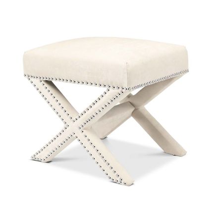 A delicate white velvet footstool adorned with nickel studs.