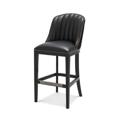 A chic black leather and velvet bar stool with antique brass studding
