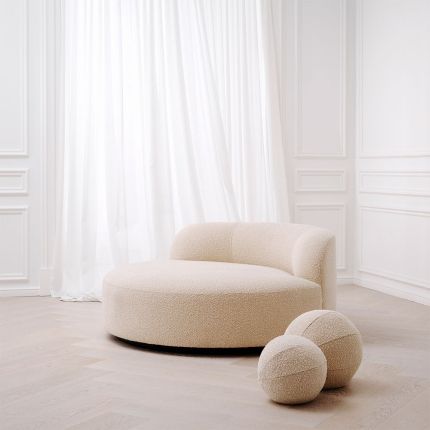 A luxurious round sofa by Eichholtz with a dreamy boucle cream upholstery and a sleek black base