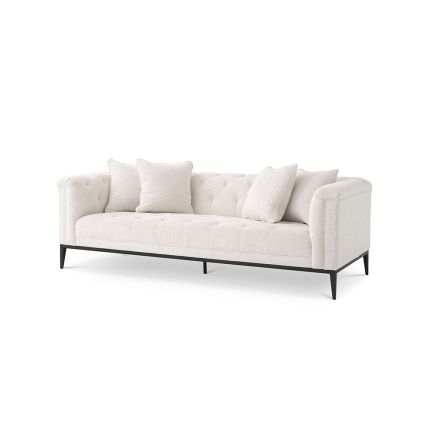A stunningly stylish sofa by Eichholtz featuring a Lyssa off-white upholstery with subtle curves, deep buttoned stitching and finished with a black gunmetal base and four scatter cushions